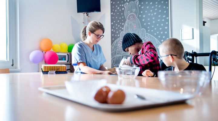 Kinder-Reha Schweiz, Wohngruppe, Pflegefachfrau bäckt mit zwei Patient*innen Kuchen
