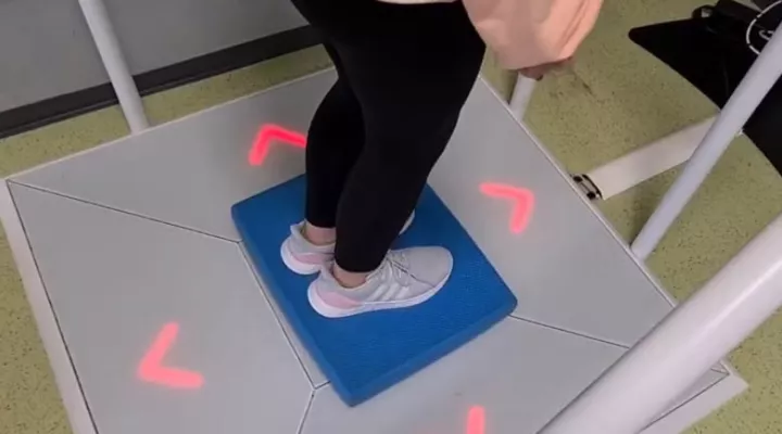 Ein Kind steht auf einer quadratischen Platte, rundherum leuchten rote Pfeile.