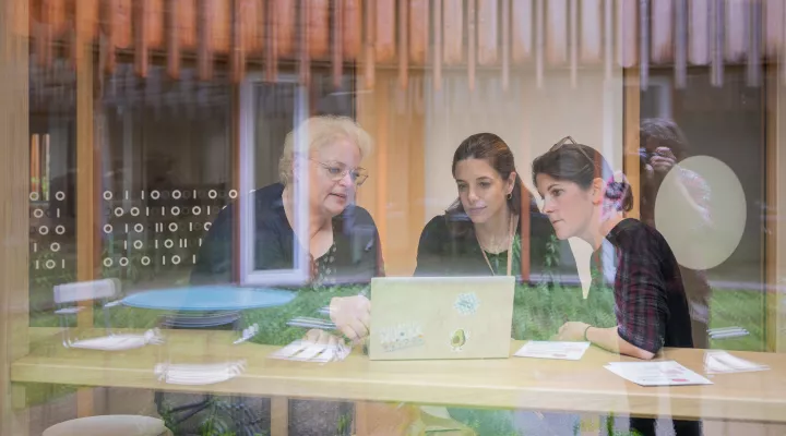 Drei Mitarbeiterinnen des Kinderspitals sitzen bei einer Besprechung mit Laptop an einem Tisch