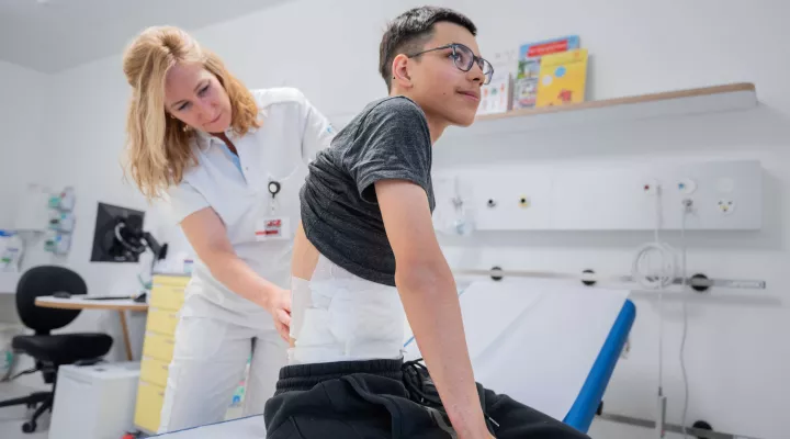 Dr. Sophie Böttcher untersucht Rücken von Patient Diego.