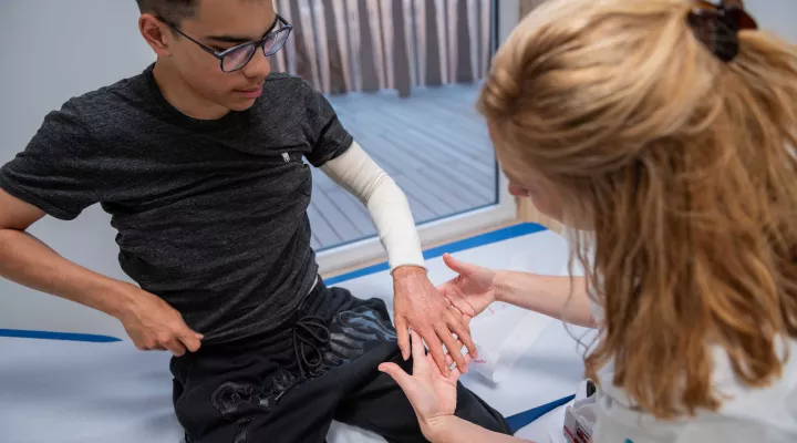 Dr. Sophie Böttcher untersucht eingewickelten Arm von Patient Diego.