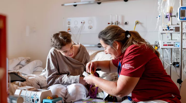 Lehrperson mit Patient in einem Patientenzimmer des Kinderspitals Zürich