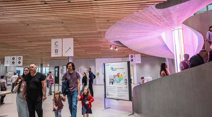 Besuchende im Hauptfoyer des Kinderspitals mit beleuchteter Rundtreppe