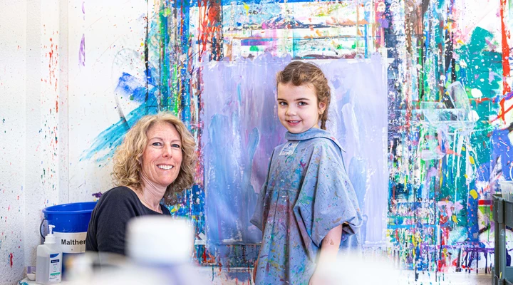 Patientin Vivian in der Kinder-Reha Schweiz präsentiert ihr gemaltes Bild auf einer Leinwand.