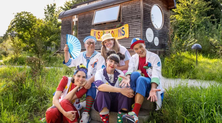 Die fünf Spitalclowns des Kinderspitals Zürich sitzen auf der Wiese vor ihrem Zirkuswagen