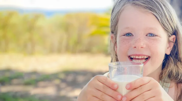 Ein Mädchen hält in den Händen einen Glass voller Milch