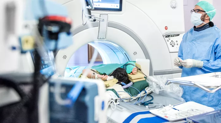 chirurgischer Eingriff im Computertomograph, Arzt kontrolliert am Bildschirm die Position der Nadel