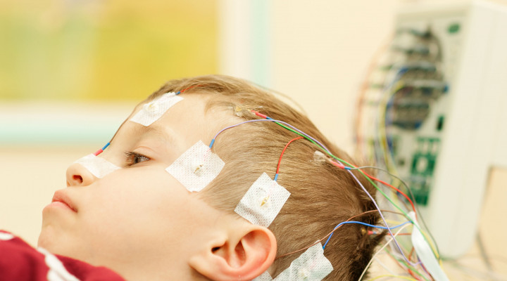 Kleiner Junge mit farbigen Elektroden auf dem Kopf während eines EEG