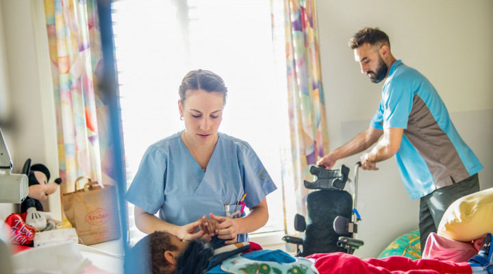 Kinder-Reha Schweiz, Pflegefachfrau zieht ein Kind im Bett an