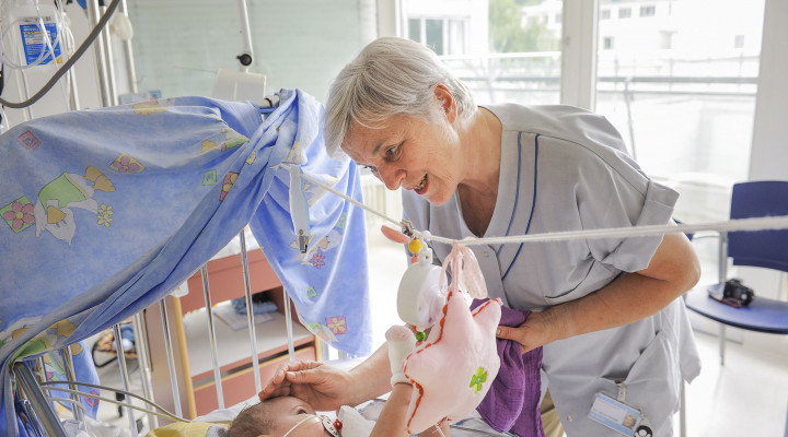 Eine freiwillige Helferin spielt mit einem Baby auf der Neonatologie
