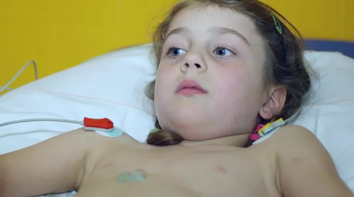 Mädchen oben ohne mit befestigten Drähten am Körper liegt auf dem Bett. 