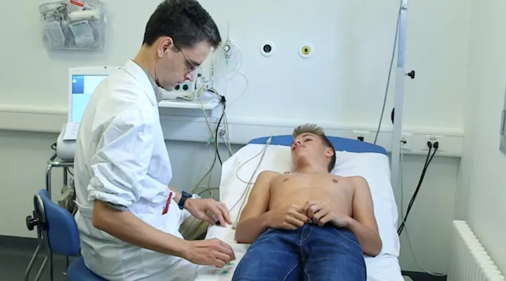 Ein Junge liegt oben ohne auf der Liege, ein Arzt untersucht ihn.