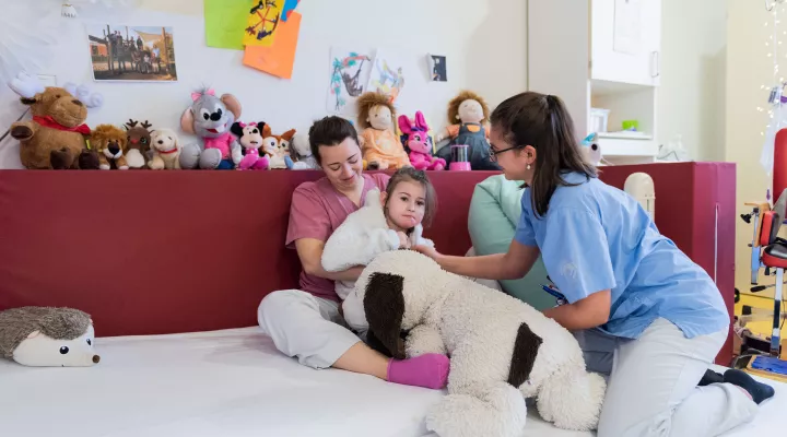 Zwei Pflegefachfrauen helfen einem Mädchen mit einer Behinderung