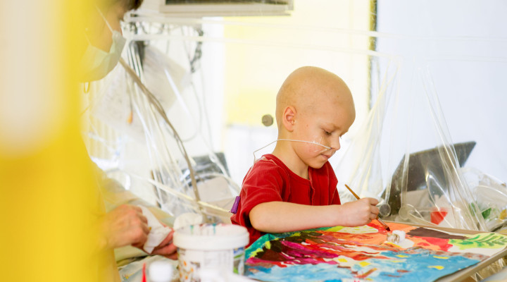 Ein krankes Kind malt ein Bild mit während der Kunsttherapie