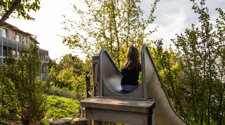 Mädchen in Rückenansicht auf der Rutschbahn des Kinderspital Zürichs