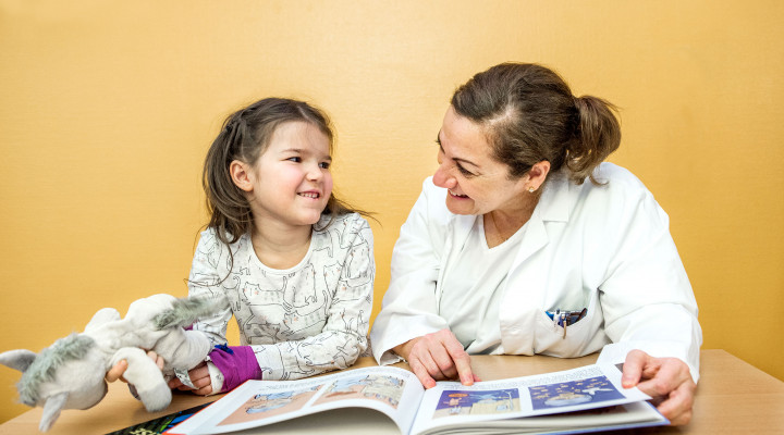 Moyamoya, ​Prof. Dr. med. Nadia Khan, Leitende Ärztin, erklärt einer Patientin im Spitalzimmer die Krankheit mit einem Kinderbuch