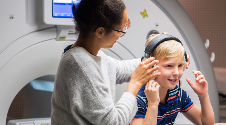 Ein Junge setzt die Kopfhörer auf den Kopf kur vor einer MRI Untersuchung