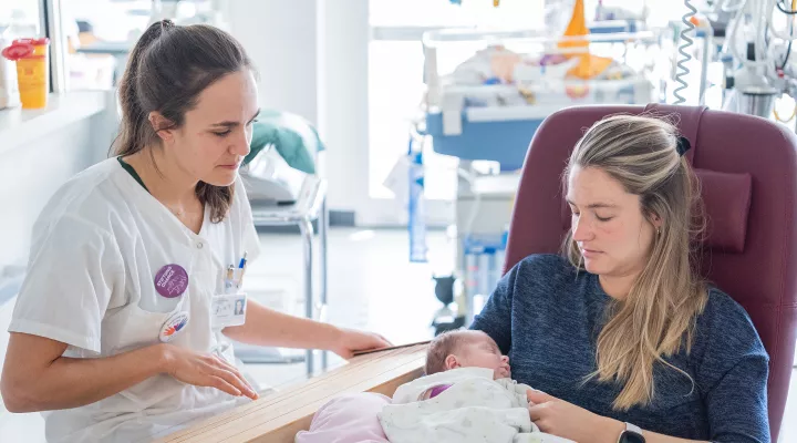 Die Musiktherapeutin spielt Monochord während eine Mutter das kranke Kind in den Armen hält