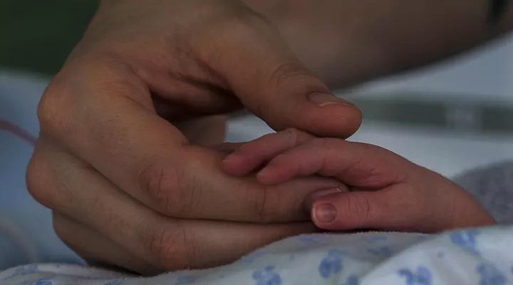 Mutter hält Händchen von krankem Baby