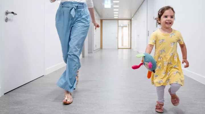 Neuropädiatrie Bewegungsstörung, kleines Mädchen rennt im Gang mit der Mutter