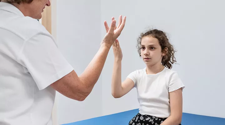 Neuropädiatrie, seltene Krankheiten, Ärztin macht führt mit einer Patientin einen Handtest durch