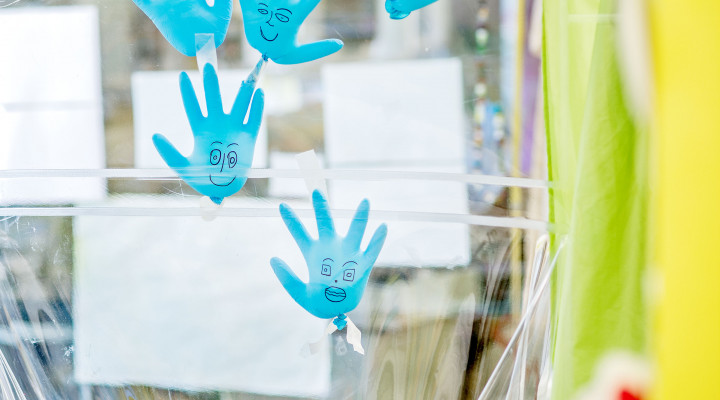 Blaue Plastikhandschuhe mit aufgemalten Gesichtern kleben an der Scheibe der Kabine, Stammzellentransplantation
