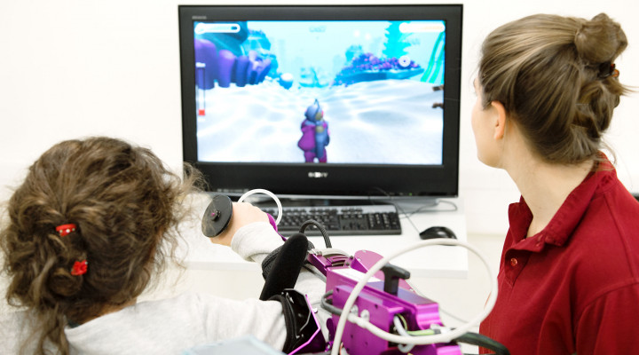 Kinder-Reha Schweiz, Robotik, Mädchen mit Armroboter und Bildschirm