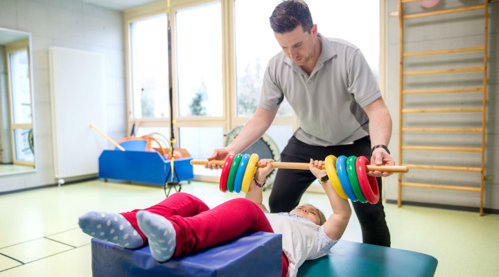 Kinder-Reha Schweiz, Sporttherapie, Therapeut mit Patientin beim Muskeltraining