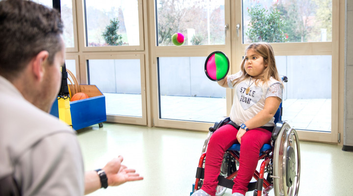 Kinder-Reha Schweiz, Sporttherapie, Therapeut und Patientin spielen mit Ball