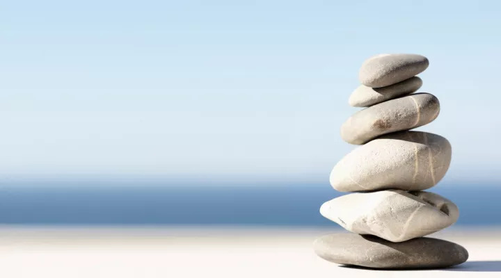 Ein Turm aus Steinen vor blauem Hintergrund.