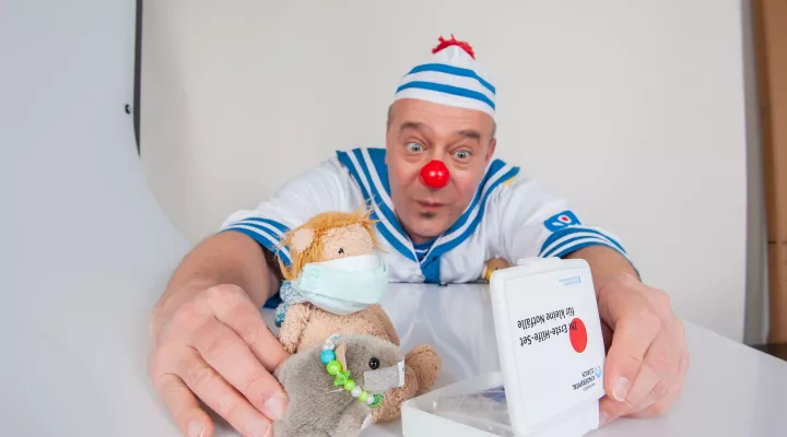Spitalclown Dada posiert mit einem Erstehilfeset