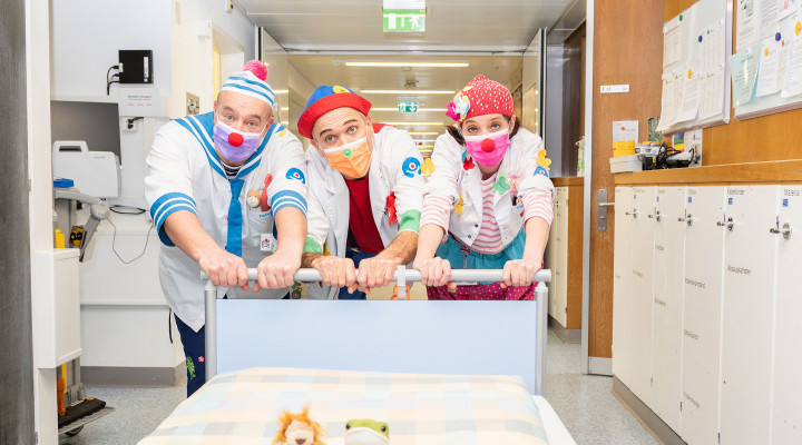 Spitalclowns Flippa Dada und Knopf schieben ein Patientenbett auf der Bettenstation des Kinderspitals Zürich.