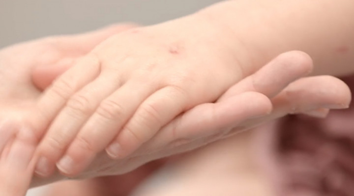 Eine Kinderhand liegt auf der Handfläche einer Erwachsenenhand.
