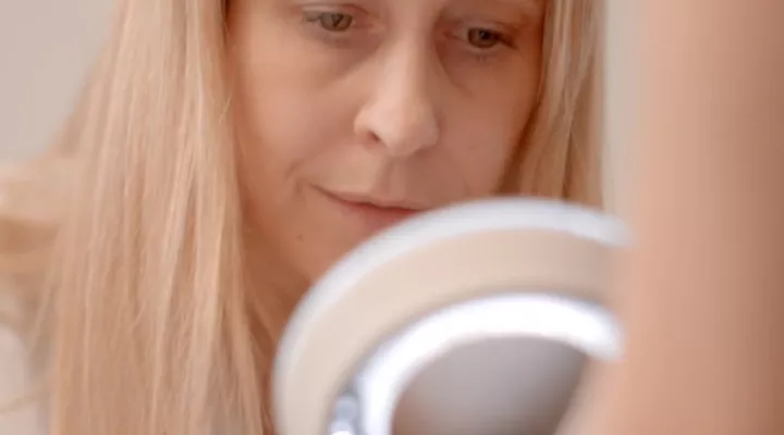 Eine Ärztin mit blonden langen Haaren schaut durch einen leuchtenden Ring.