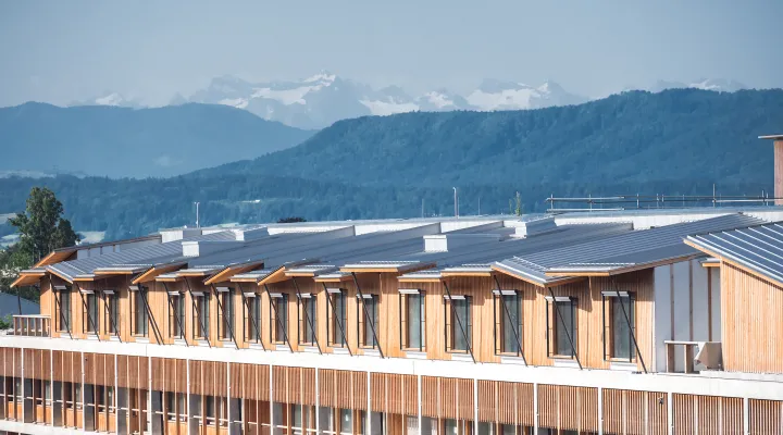 Ein Architekturfoto zeig den Neubau, im Hintergrund sieht man verschneite Berge 