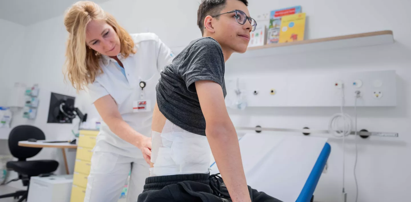 Dr. Sophie Böttcher untersucht Rücken von Patient Diego.