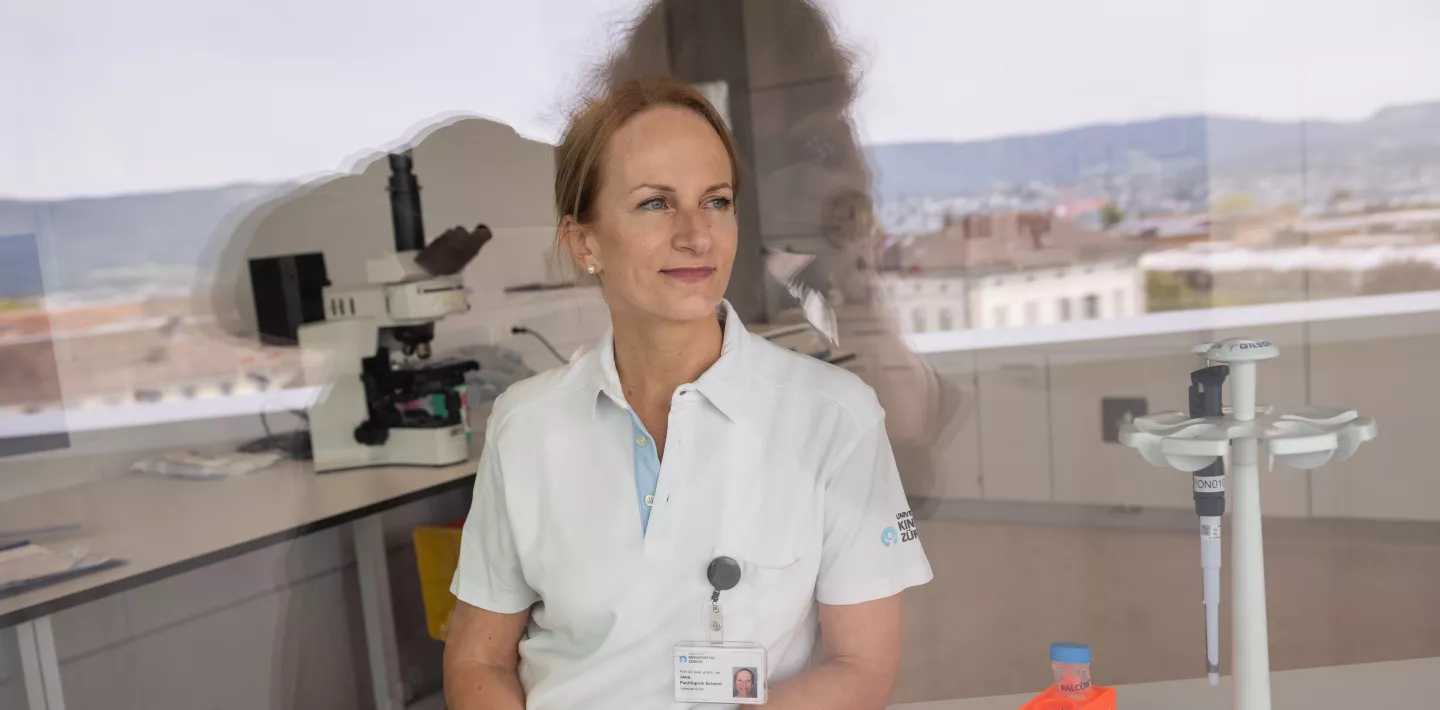 Die Ärztin Jana   Pachlopnik Schmid sitzt in Arbeitskleidung im Labor an einem Tisch