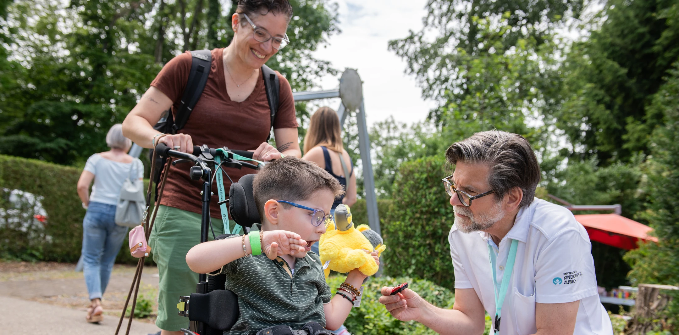 Chefarzt der Kinder-Reha Schweiz begrüsst ein Kind und Frau im Rollstuhl