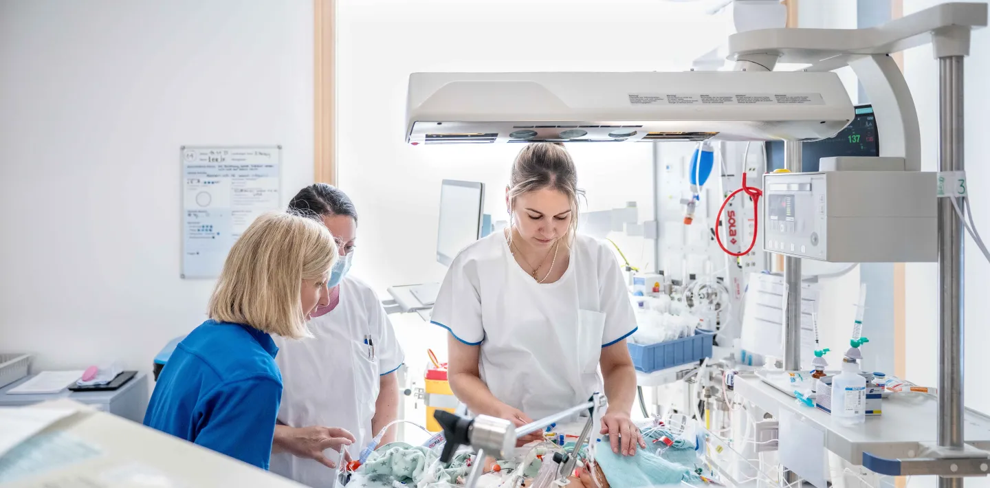 Eine Berufsbildnerin und zwei Pflegefachfrauen pflegen ein Baby auf der Intensivstation im Kinderspital Zürich