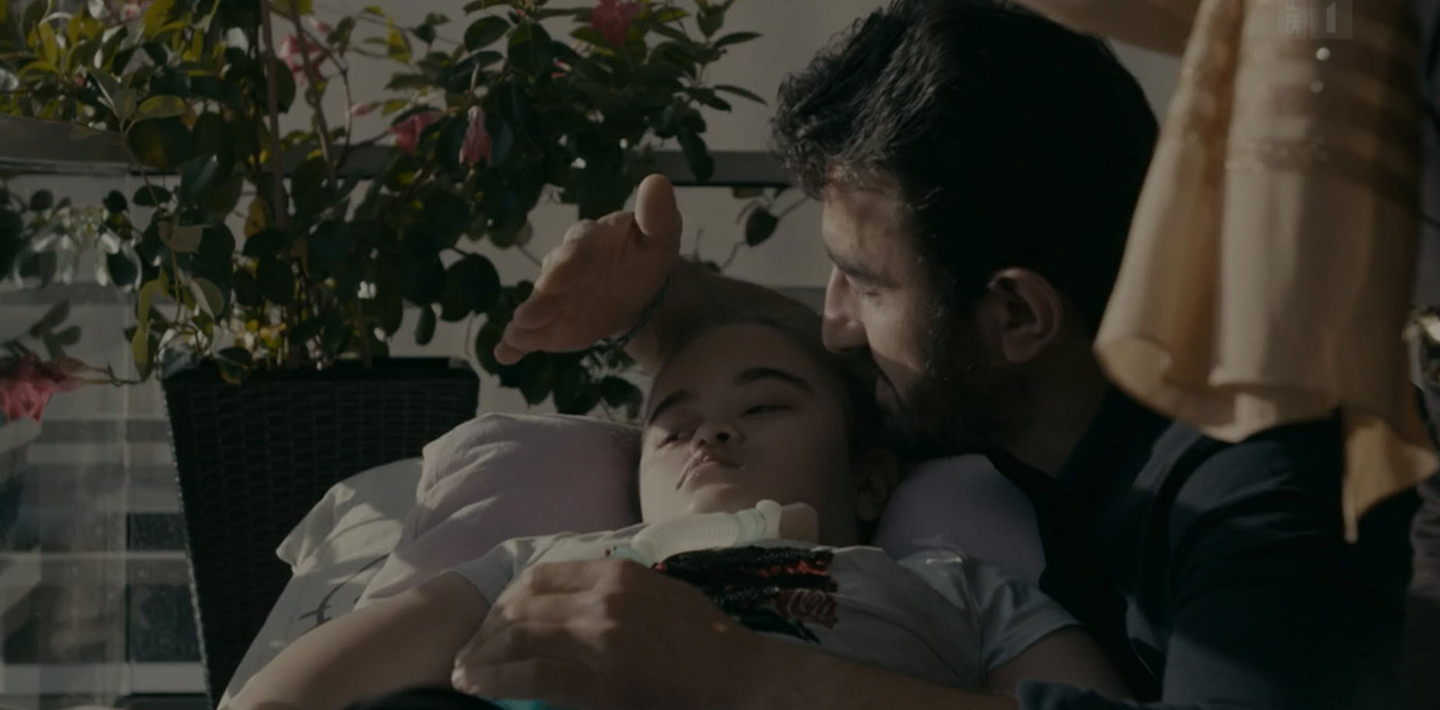 Ein Vater schützt seine totkranke Tochter mit seiner Hand vor der Sonne.
