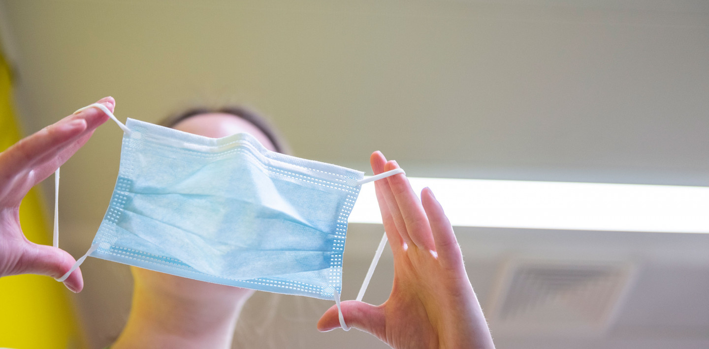 Eine Pflegefachperson zieht eine chirurgische Maske während der Corona Pandemie an