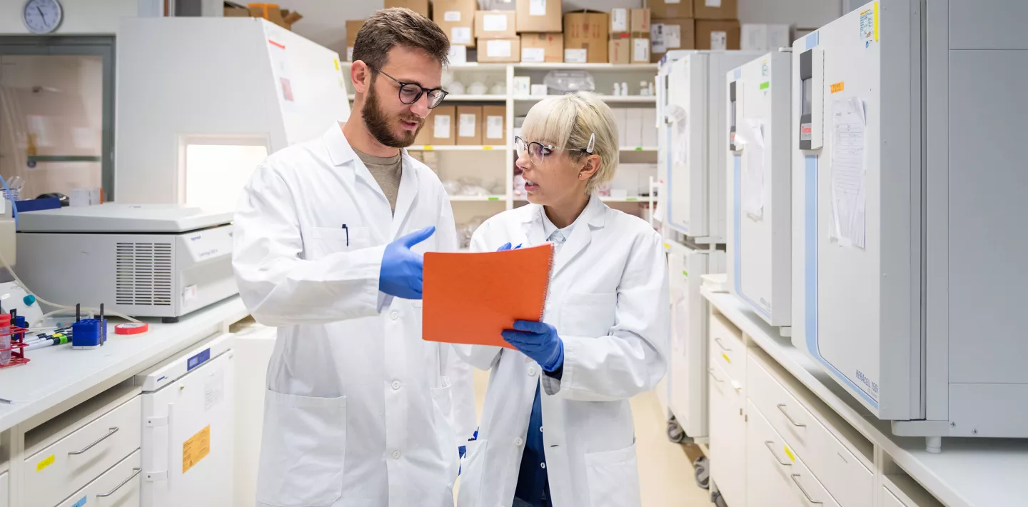 Eine Forscherin und ein Forscher in einer Besprechung im Labor