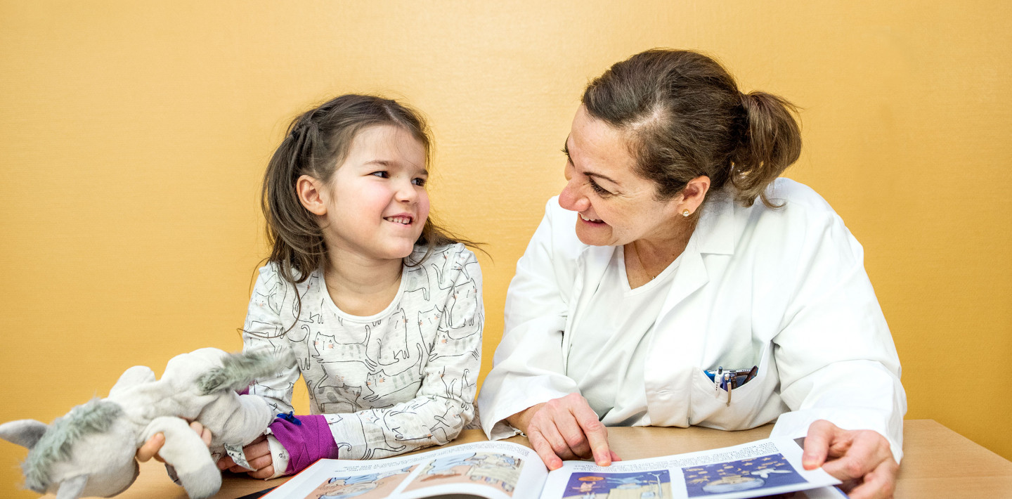 Moyamoya, ​Prof. Dr. med. Nadia Khan, Leitende Ärztin, erklärt einer Patientin im Spitalzimmer die Krankheit mit einem Kinderbuch
