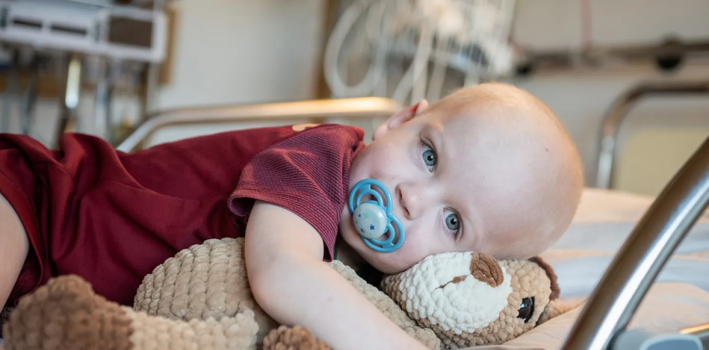 umarmt sein Plüschtier, während er im Spitalbett liegt.