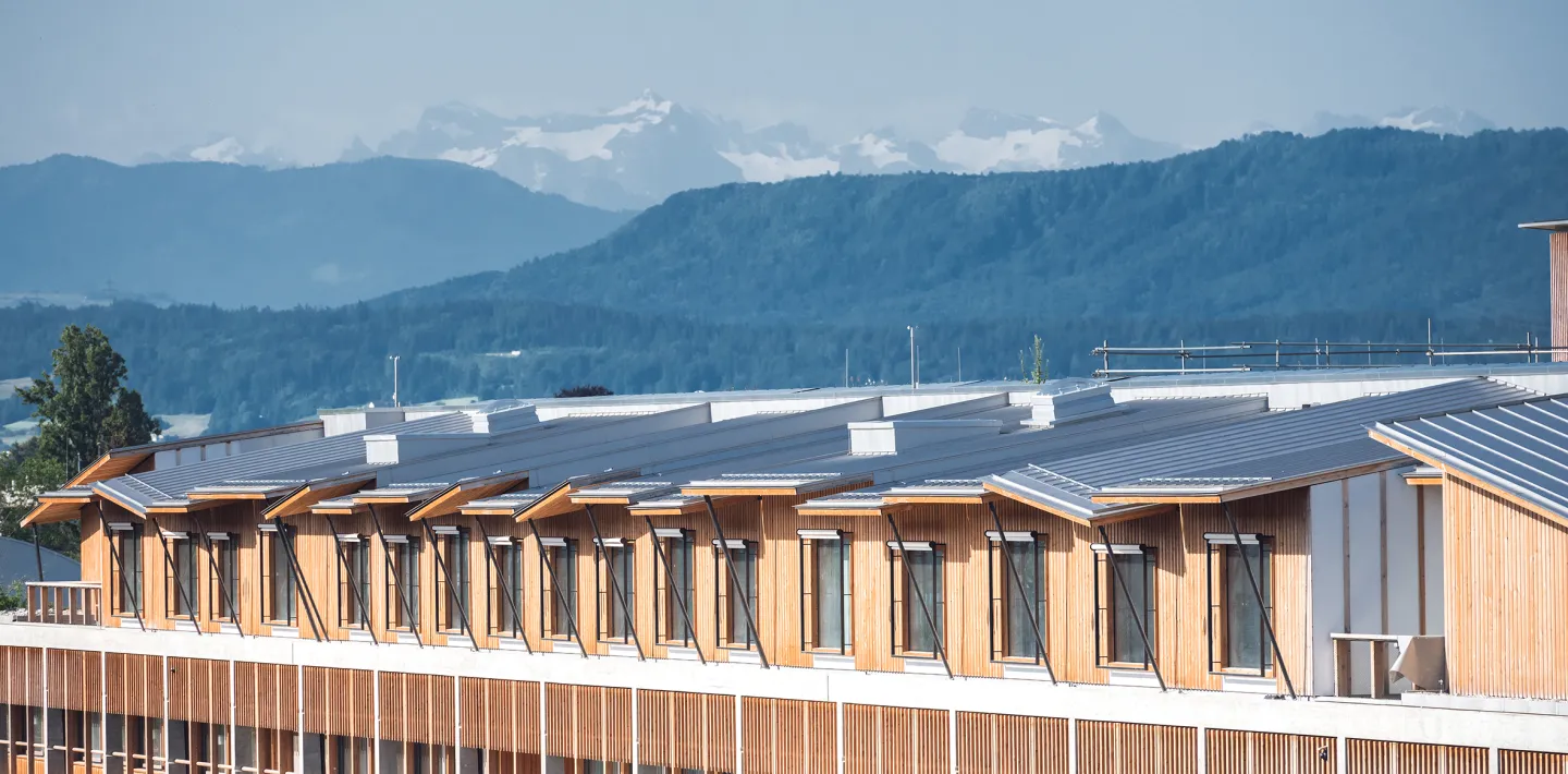 Ein Architekturfoto zeig den Neubau, im Hintergrund sieht man verschneite Berge 