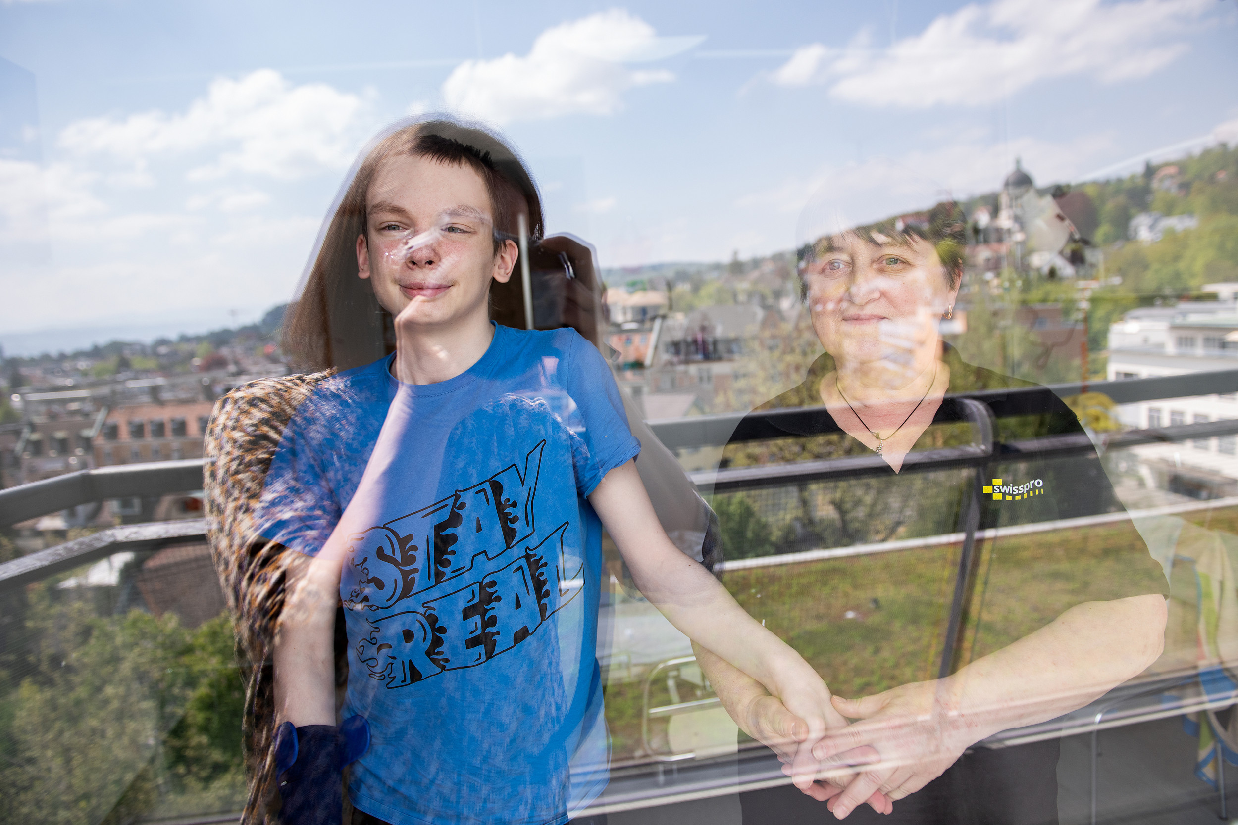 Ein 15-jährige Junge mit einem Hirntumor schaut aus dem Fenster seines Zimmers im Kinderspital Zürich und seine Oma hält ihn seine Hand 