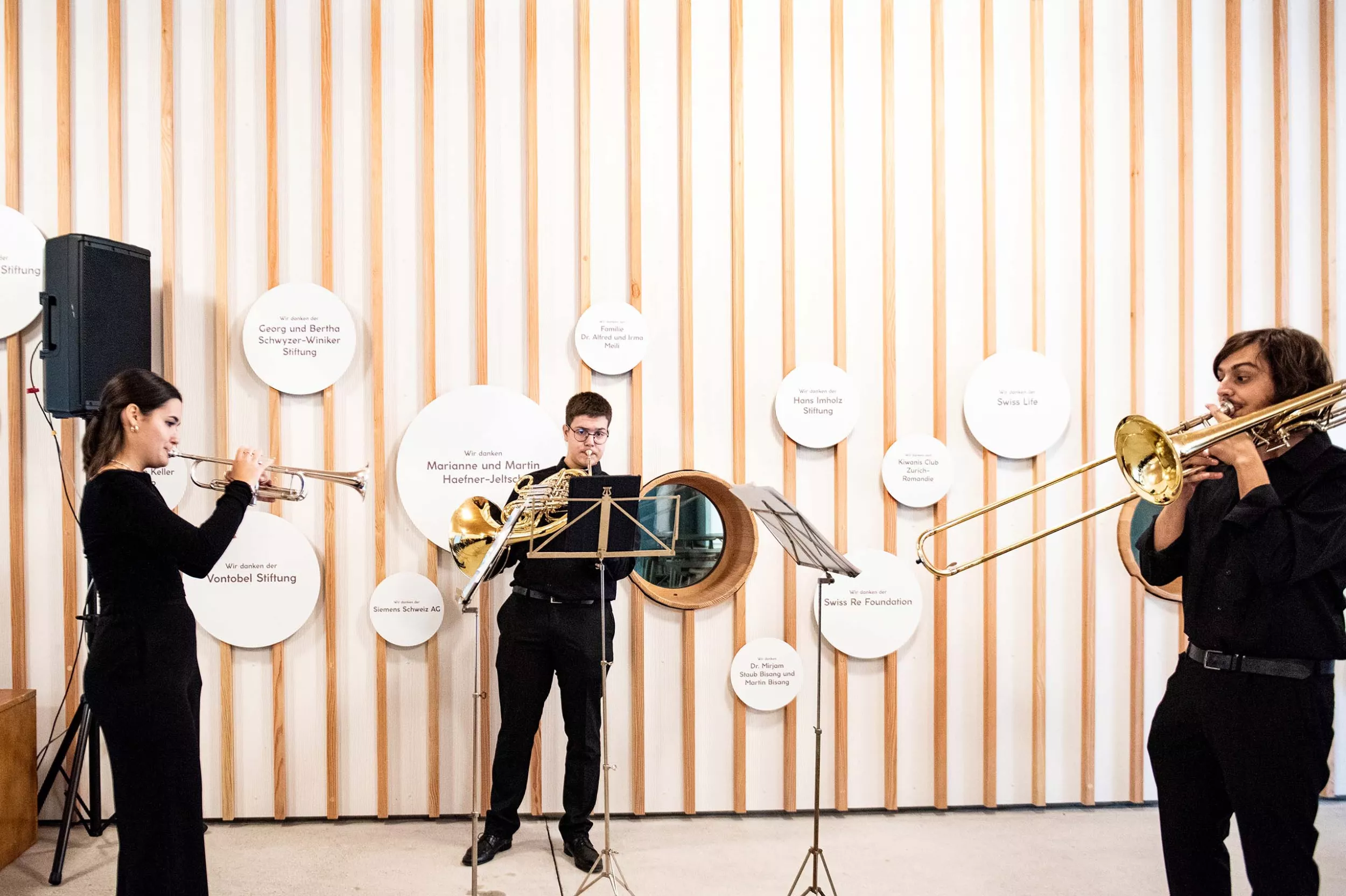 Zwei Musiker und eine Musikerin spielen Blechblasinstrumente vor dem Eingang des Kinderspitals Zürich