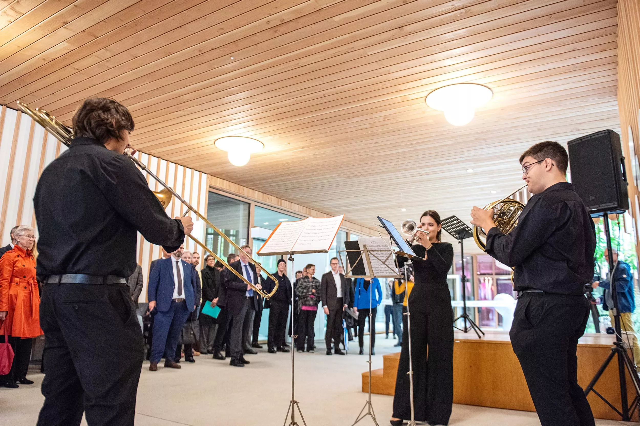 Zwei Musiker und eine Musikerin spielen Blechblasinstrumente vor dem Eingang des Kinderspitals Zürich