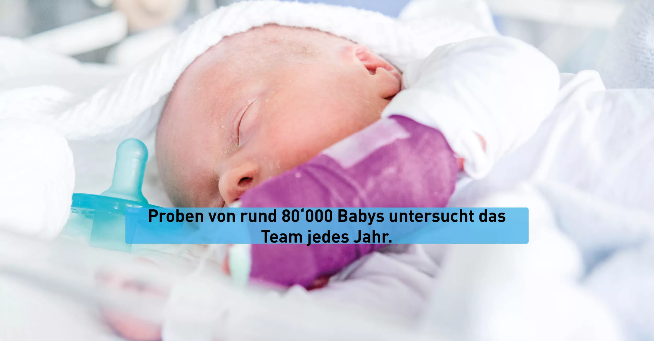Ein Baby liegt im Bett und schlägt. Am Arm trägt es einen Verband.