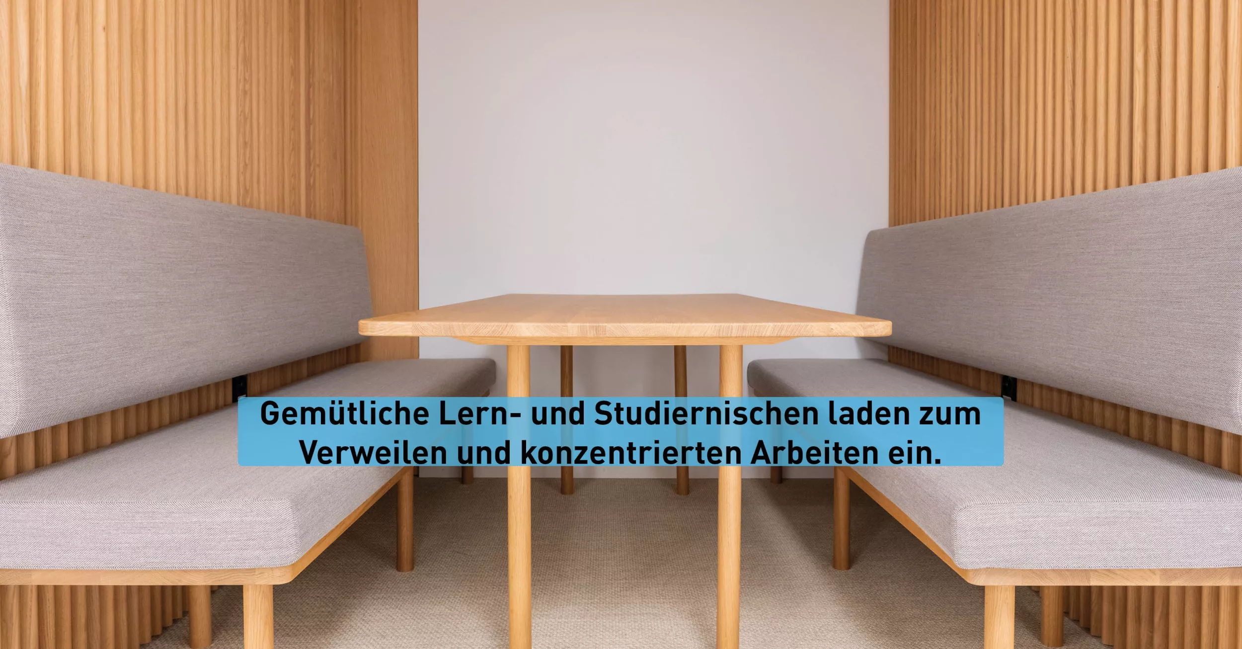 Eine Lernnische mit zwei gepolsterten Sitzbänken sowie einem Holztisch in der Mitte. Die Wände sind ebenfalls mit Holz verkleidet.